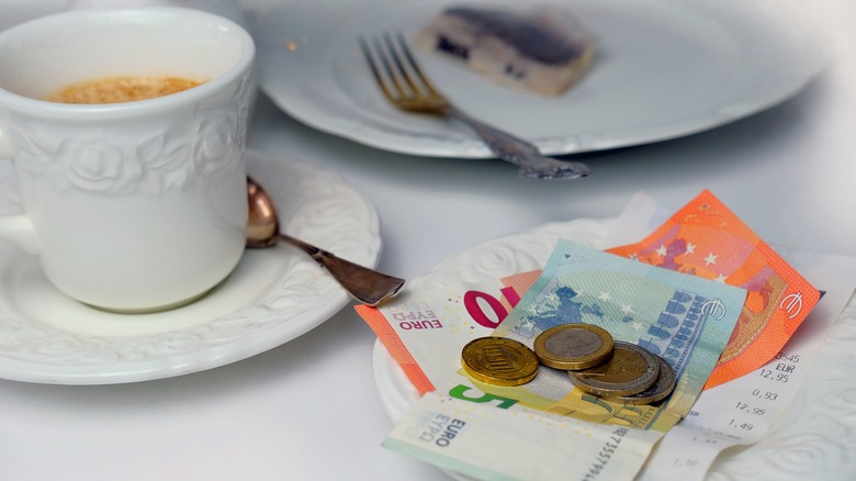 Coffee cup, bill and euros on table