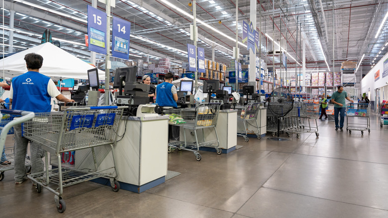 A row of cashiers stand at their registers in a Sam's Club