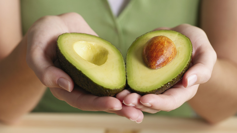 Halved avocado in hands