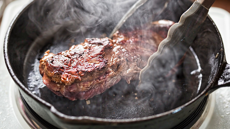 Frying steak in skillet with smoke