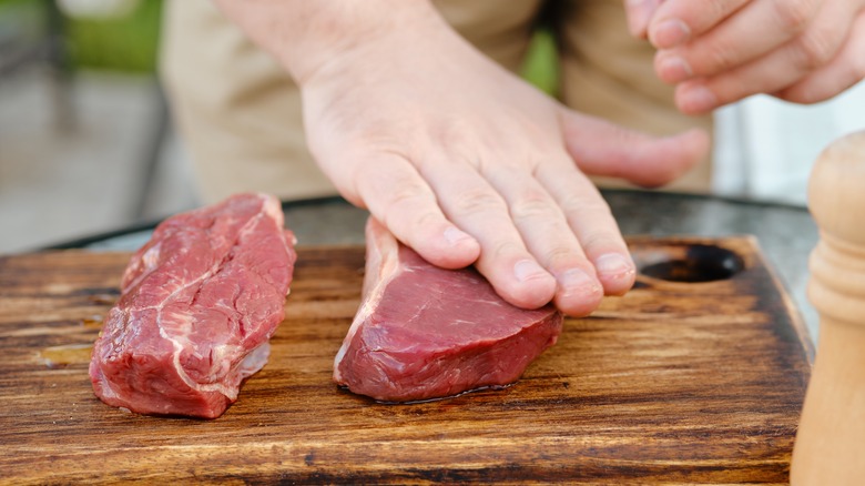 Rubbing olive oil over raw beef steaks