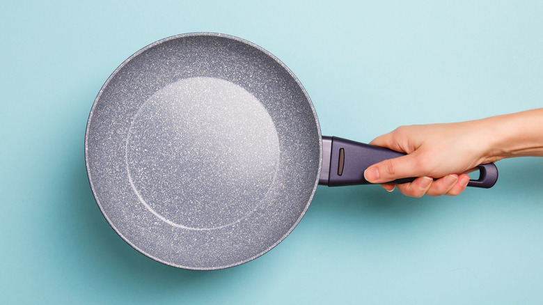 A hand holding a non-stick pan