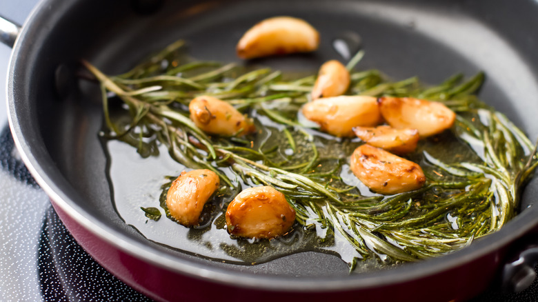 A pan with oil, garlic, and herbs