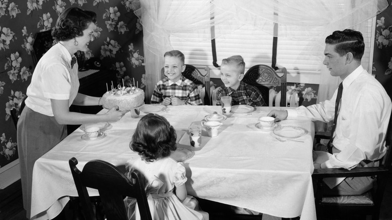 Black-and-white photo of a 1950s family sitting together at a dinner table