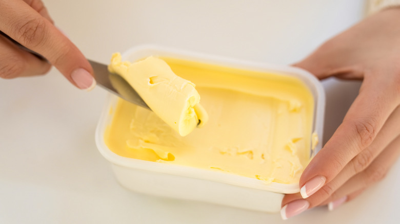 Person scooping margarine from a tub