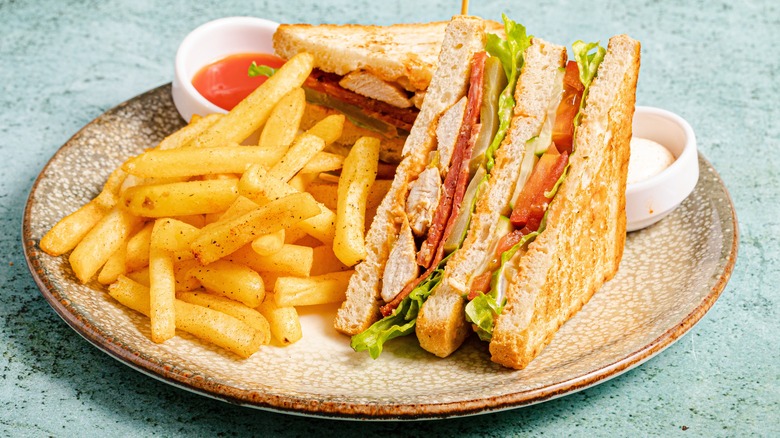 A club sandwich and fries on a plate
