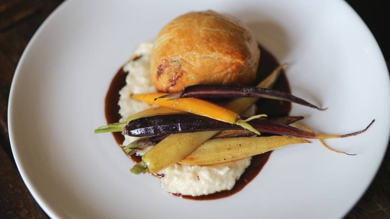 Beef Wellington with roasted vegetables on white plate