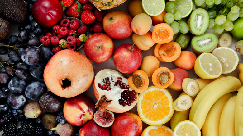 A wide array of different types of fruit laid out in a rainbow of colors.
