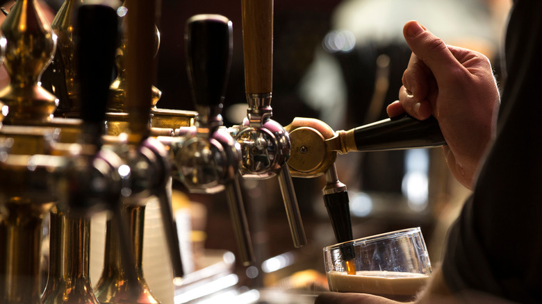 Hand pouring a stout beer from a draft