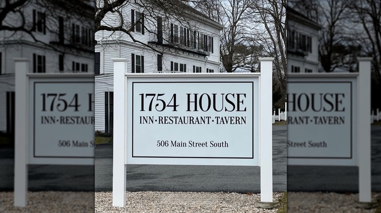 Signage outside the white exterior of 1754 House