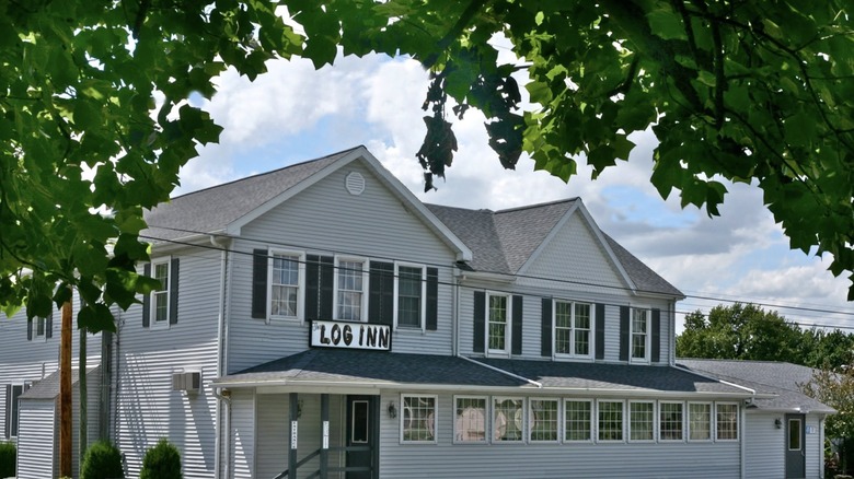 Exterior of the Log Inn seen from beneath a leafy tree branch