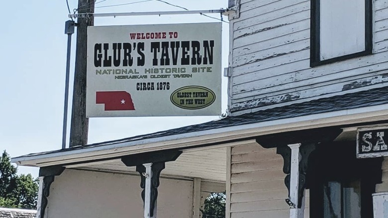 Sign for Glur's Tavern displayed above a weathered patio