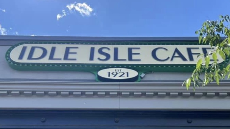 Some clouds float across a blue sky above the sign for the Idle Isle Cafe