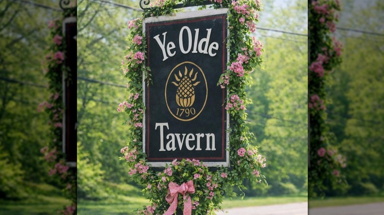 Pink flowers on a vine and a bowed wreath frame a sign for Ye Olde Tavern