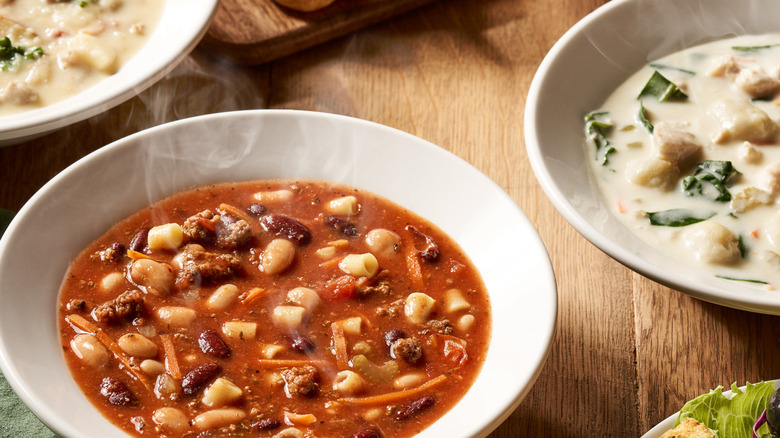 Bowls of Olive Garden soups near a salad bowl