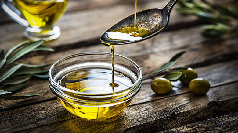 olive oil poured on spoon and glass ramekin