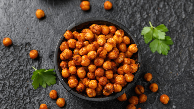 roasted chickpeas in a black bowl alongside fresh parsley