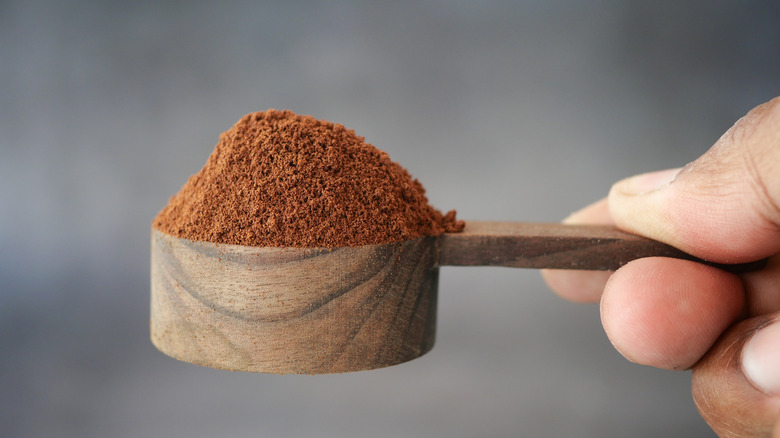 person holding espresso powder in a mounded scoop