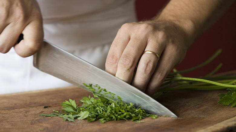 Person chopping up parsley with large knife