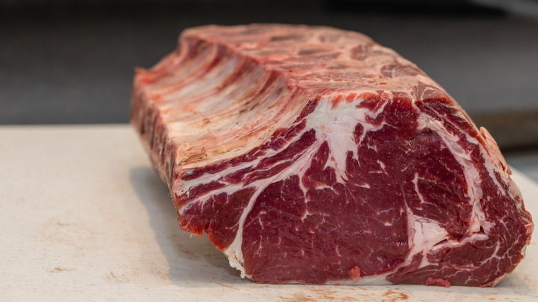 A large bone-in prime rib on a counter.