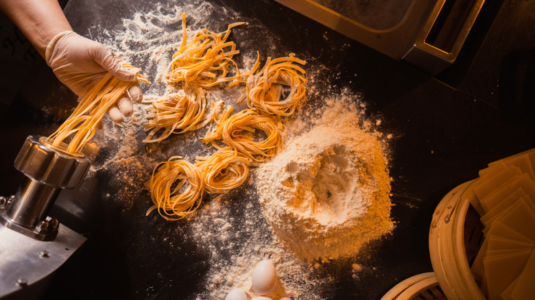 Handmade pasta from scratch on flour-covered table