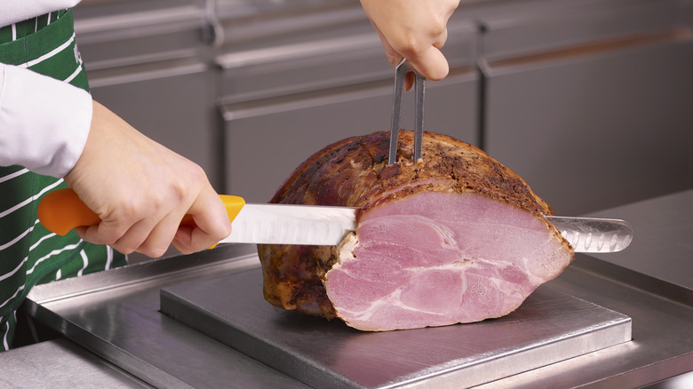 A chef slices into a whole ham