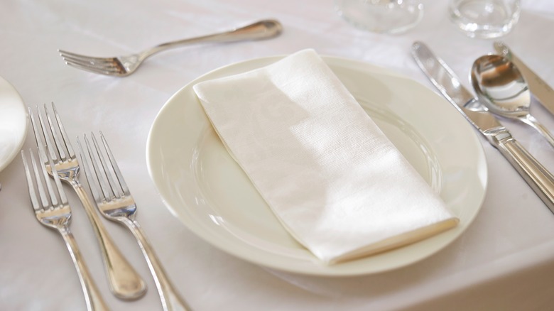 place setting with utensils on white tablecloth