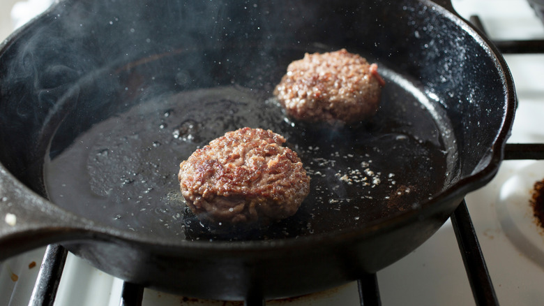 Burgers cooking in a cast iron skillet