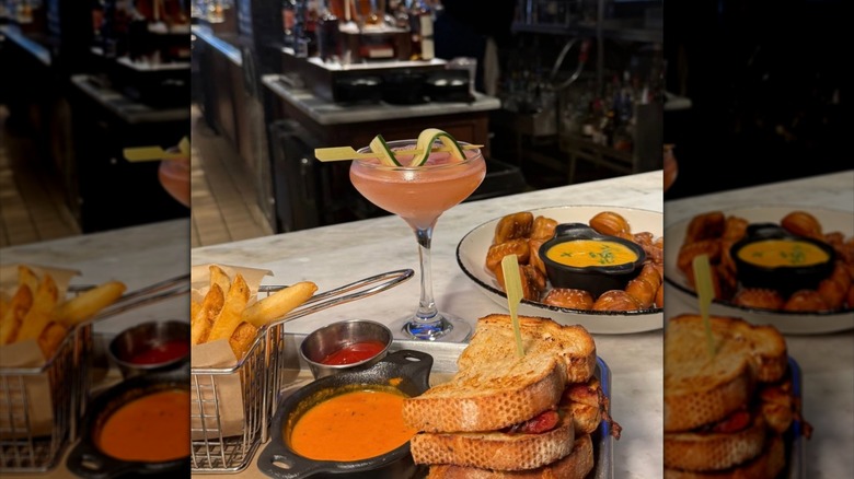 Cocktail served with pretzel bites, sandwich, tomato soup, and fries