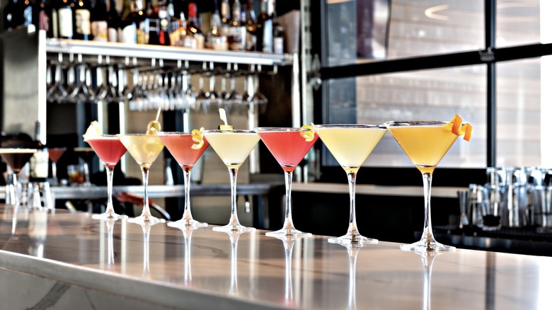 Row of colorful martinis lined up on a bar