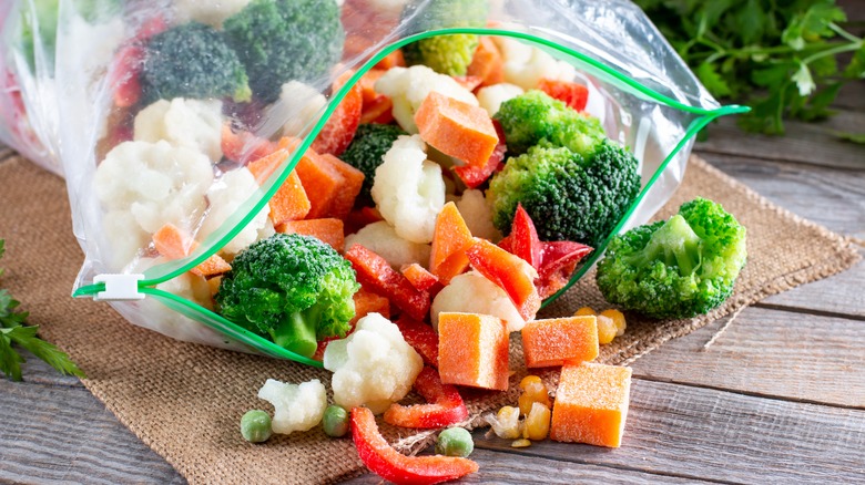Various frozen vegetables spilling out of a plastic bag