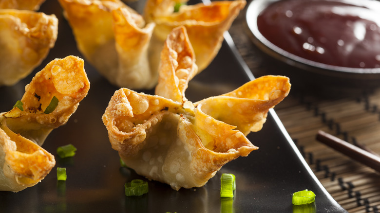Plate of crab rangoon on black plate with scallions