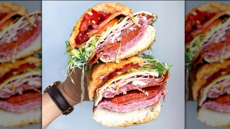 The Bomb Italian sub sandwich cut in half facing front and held in one hand