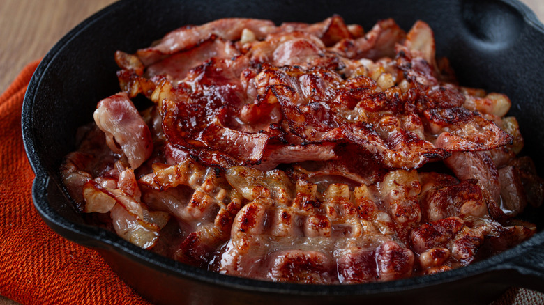 Bacon cooking in a cast iron skillet.