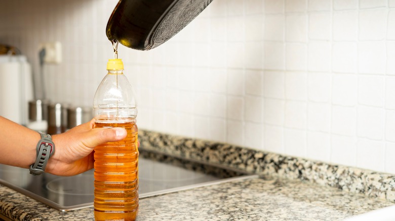 Person pouring cooking oil into a plastic bottle