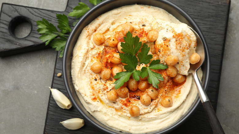 A bowl of creamy hummus topped with chickpeas, spices, and parsley