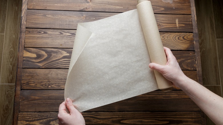 Person holding a roll of parchment paper