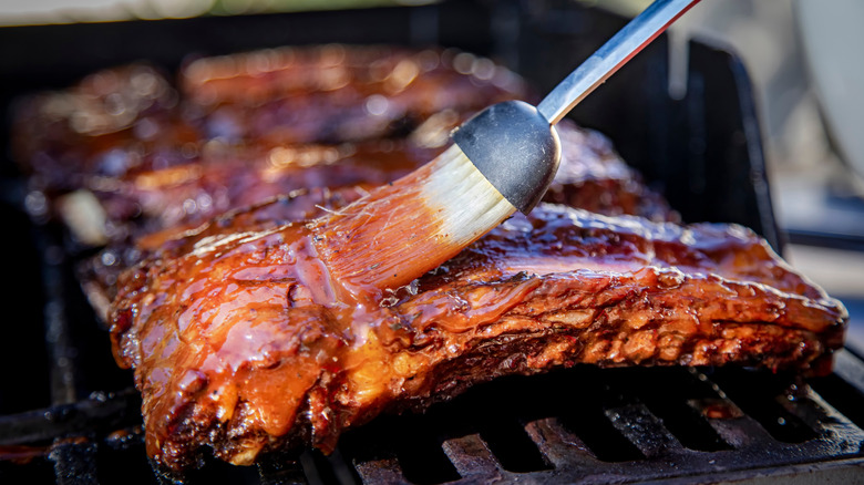 A pitmaster barbecues ribs on the grill and marinates the meat