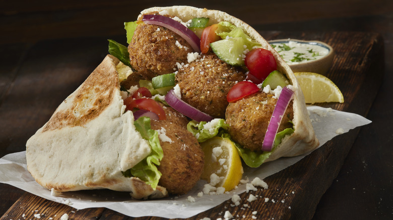 Two falafel pita sandwiches on a wooden surface