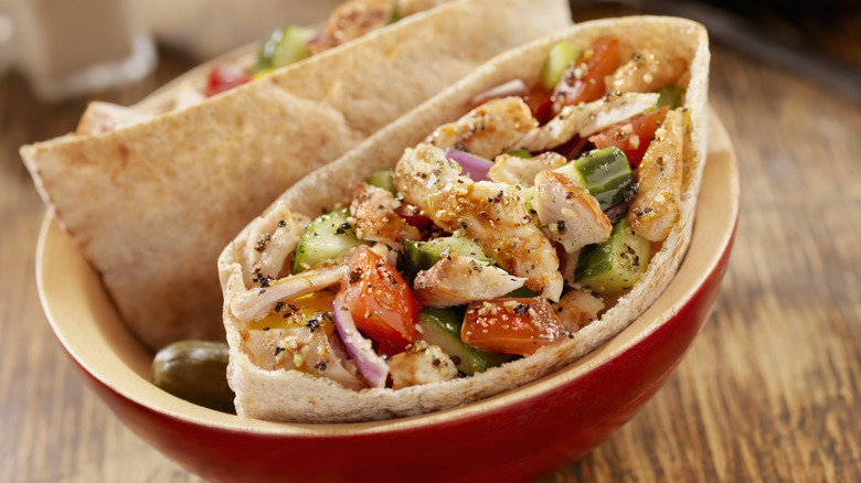 Two pitas in a bowl filled with chicken and various veggies
