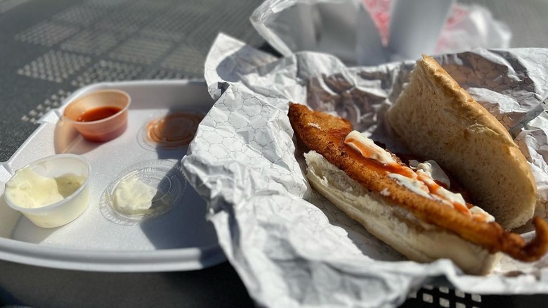 A massive fish sandwich sits in a takeout container