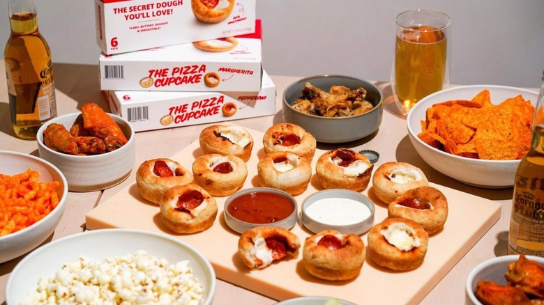 Pizza cupcakes, wings, chips and beer on table