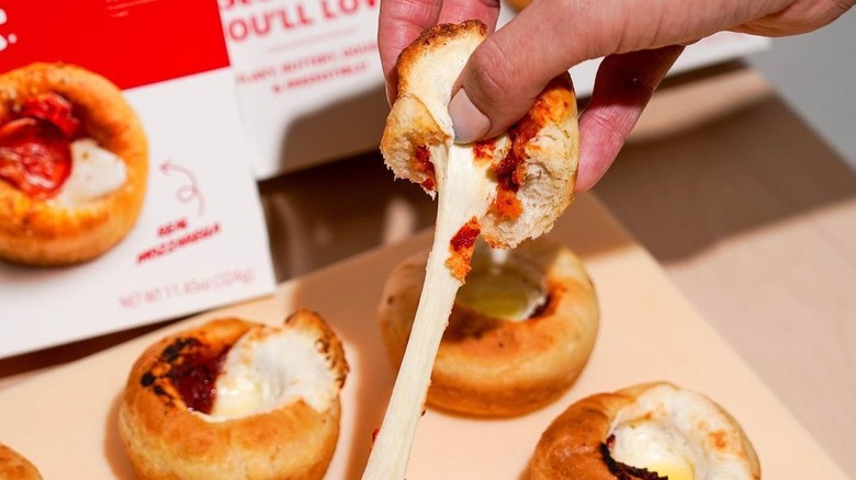 Hand pulling apart cheesy pizza cupcake