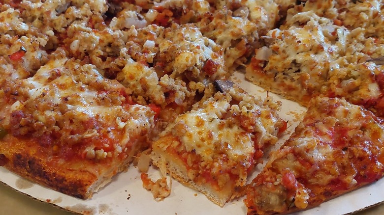 A meaty pizza from Pizza King sits on a cardboard liner