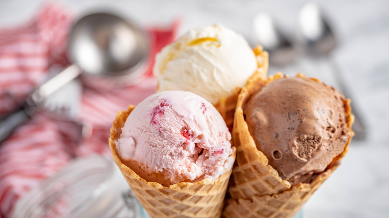 three ice cream cones with scoop in background