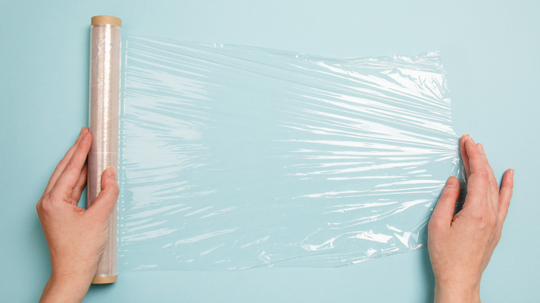 hands unrolling plastic wrap