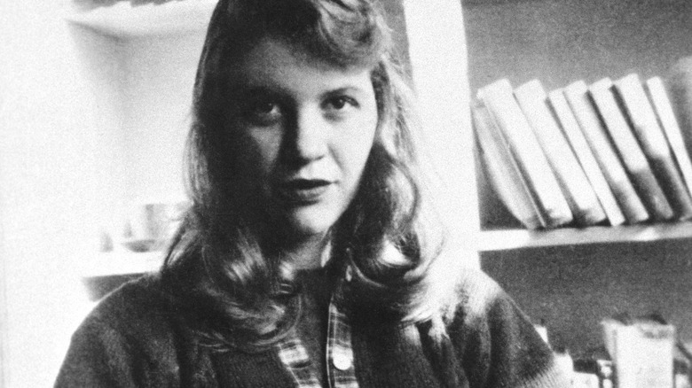 Sylvia Plath posing in front of books