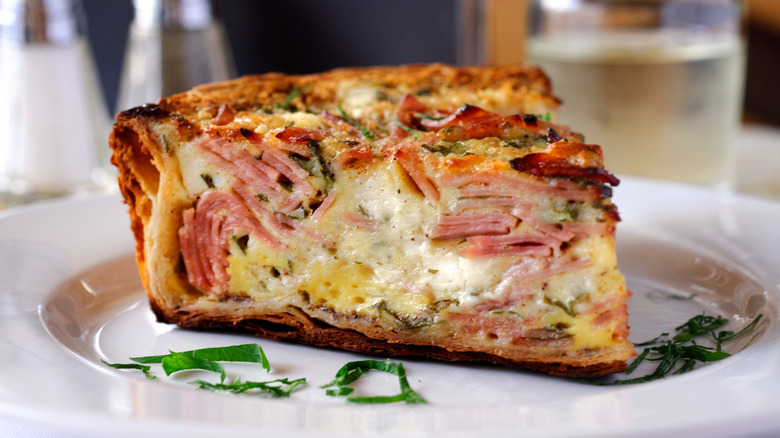 plated slice of quiche with layers of ham and cheese