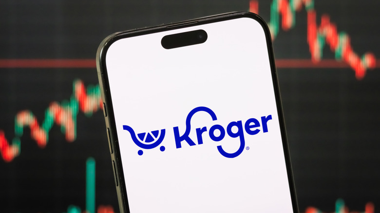 A phone displays the Kroger app logo, with visualized data in the background
