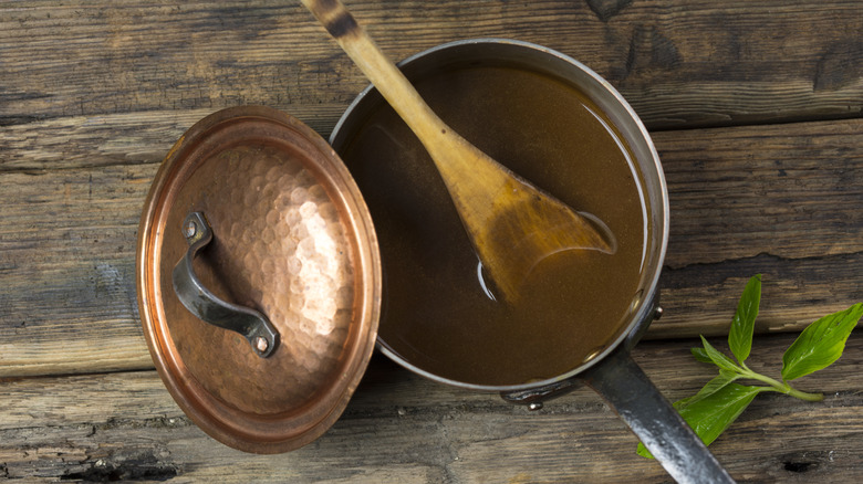 A pan of brown gravy on a wooden table